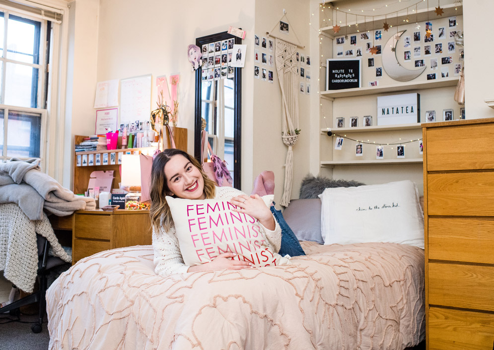 BU student Natalie Held lays on her bed in her dorm room while holding her 