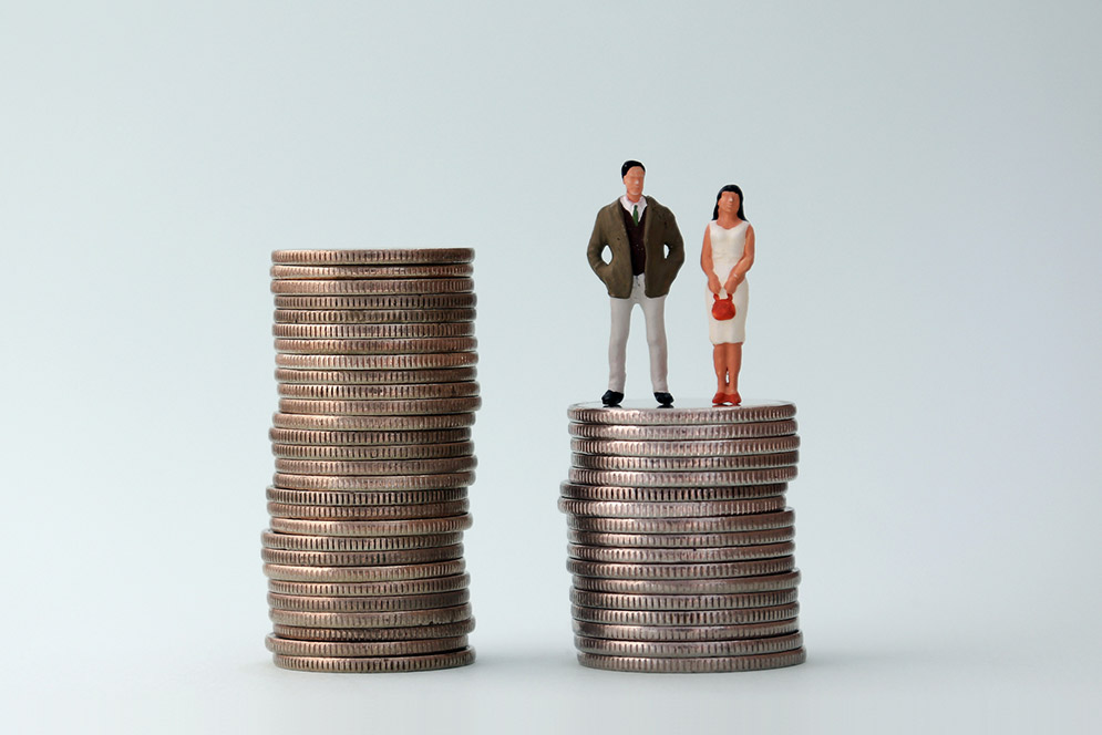 Photo of a miniature man and woman standing the same pile of change, symbolizing gender wage equality.