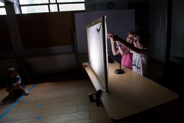 Two children play with shadow puppets