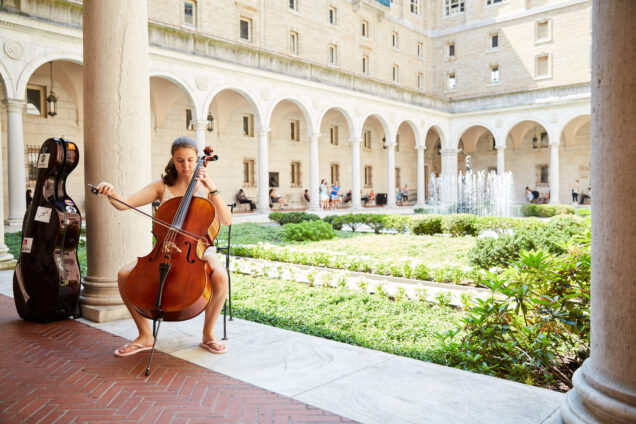 A woman plays the cello in the courtyard at the Boston Public Library during a free concert