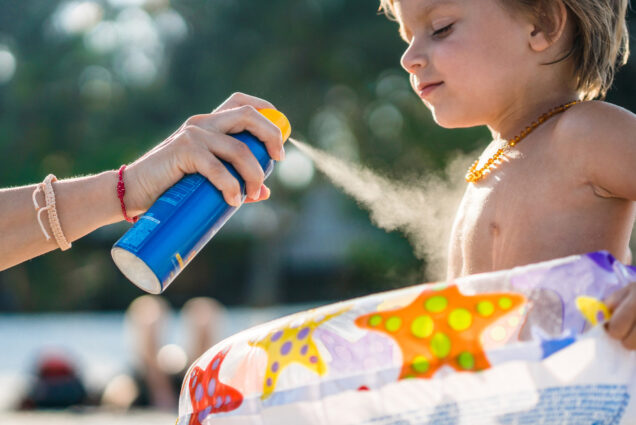 A little boy gets sprayed with sunscreen