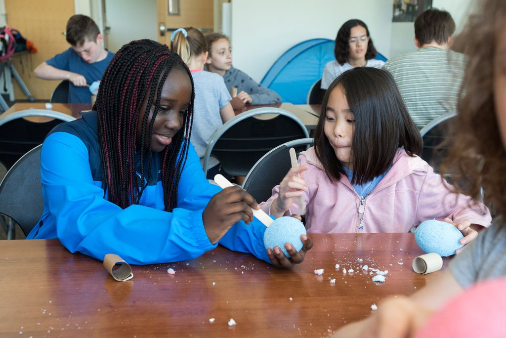 two girls create puppets using styrofoam, paper, cardboard, and fabric.