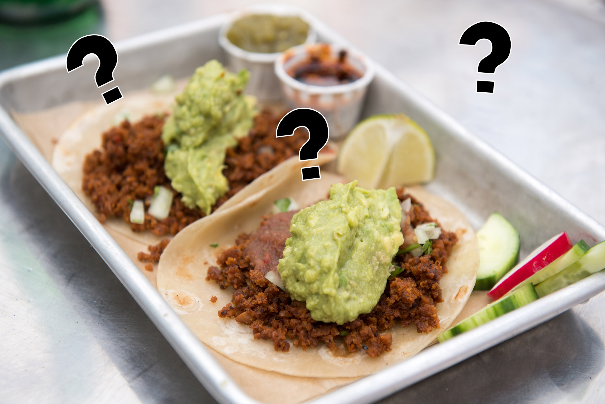 A picture of vegan chorizo tacos with question marks hanging above it