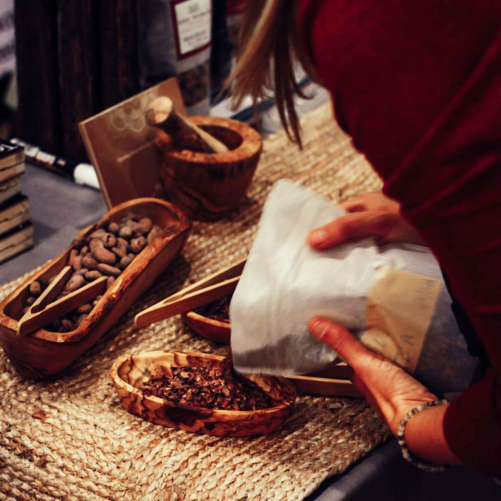 A vendor arranges a display of cacao beans and other chocolate goods on a table.