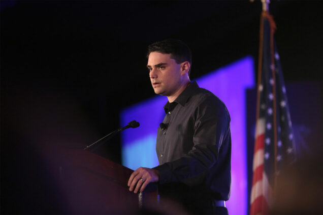 Conservative commentator Ben Shapiro speaking at a podium during a public appearance.