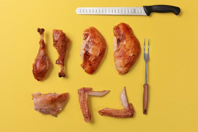 carved turkey parts next to a carving fork and knife on a yellow background