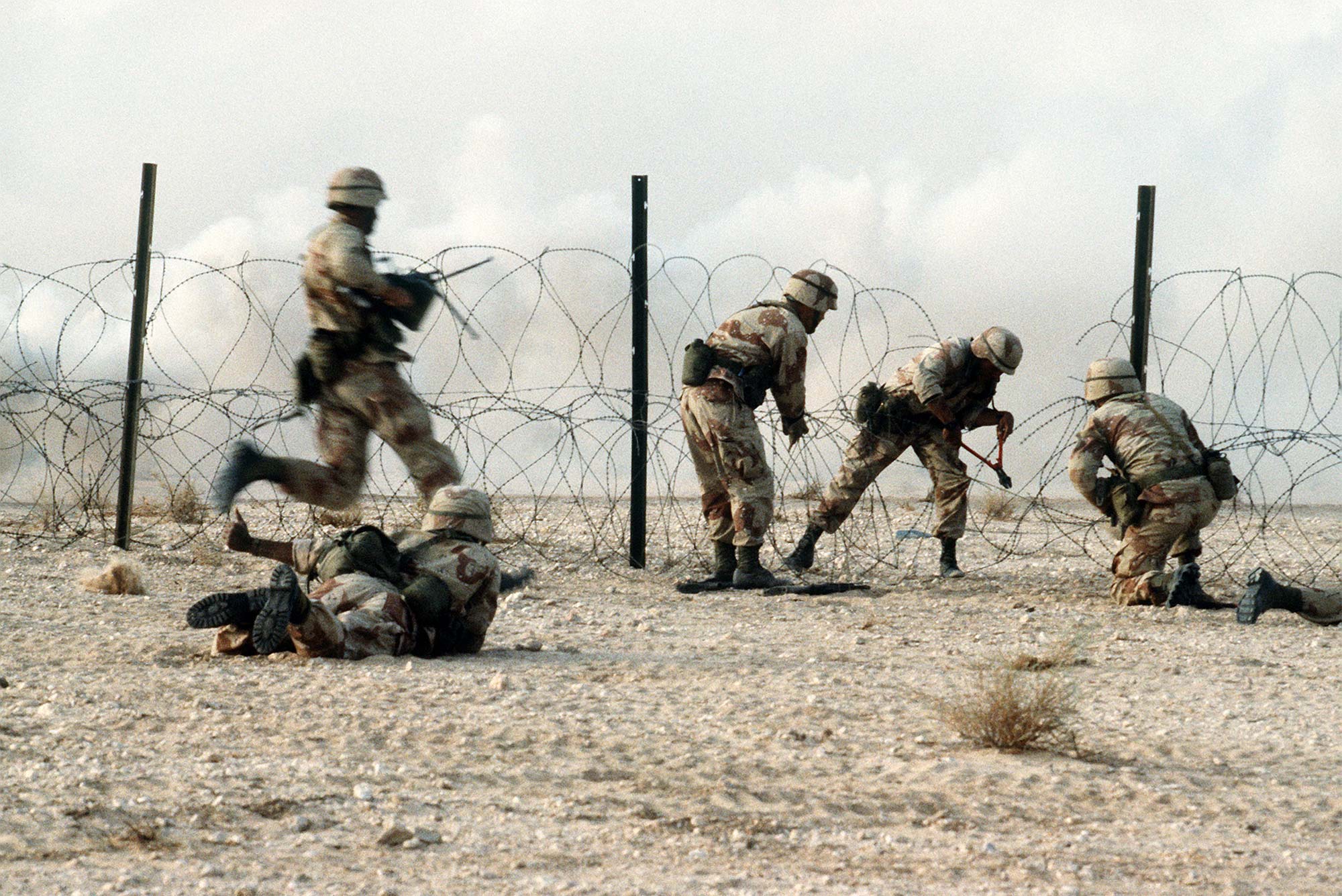 Members of the 1st Battalion, 325th Airborne Infantry Regiment, make their way through concertina wire during a live fire demonstration during Operation Desert Shield.