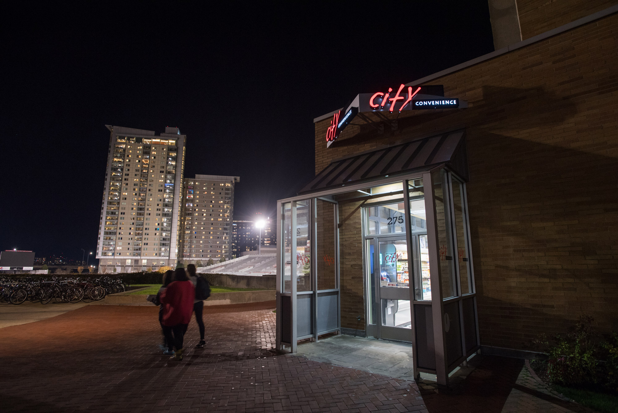 people walk out of City Convenience late at night