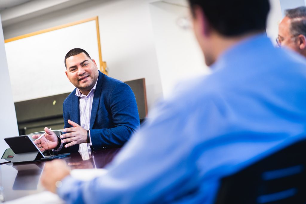 Raul Fernandez speaks with other staff members at a conference table