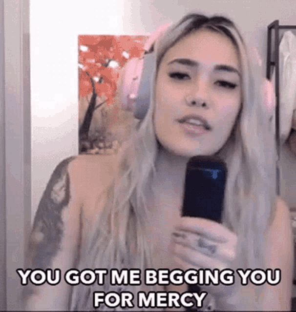 Animated GIF of a woman singing into a microphone with headphones on. Embedded text reads "You got me begging you for mercy."