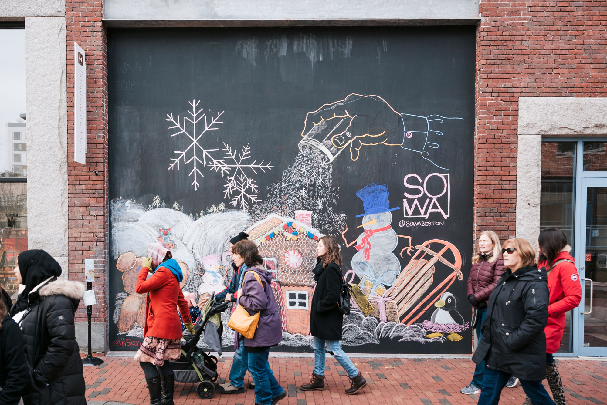 People walk in front of a mural at the SoWa Open Market