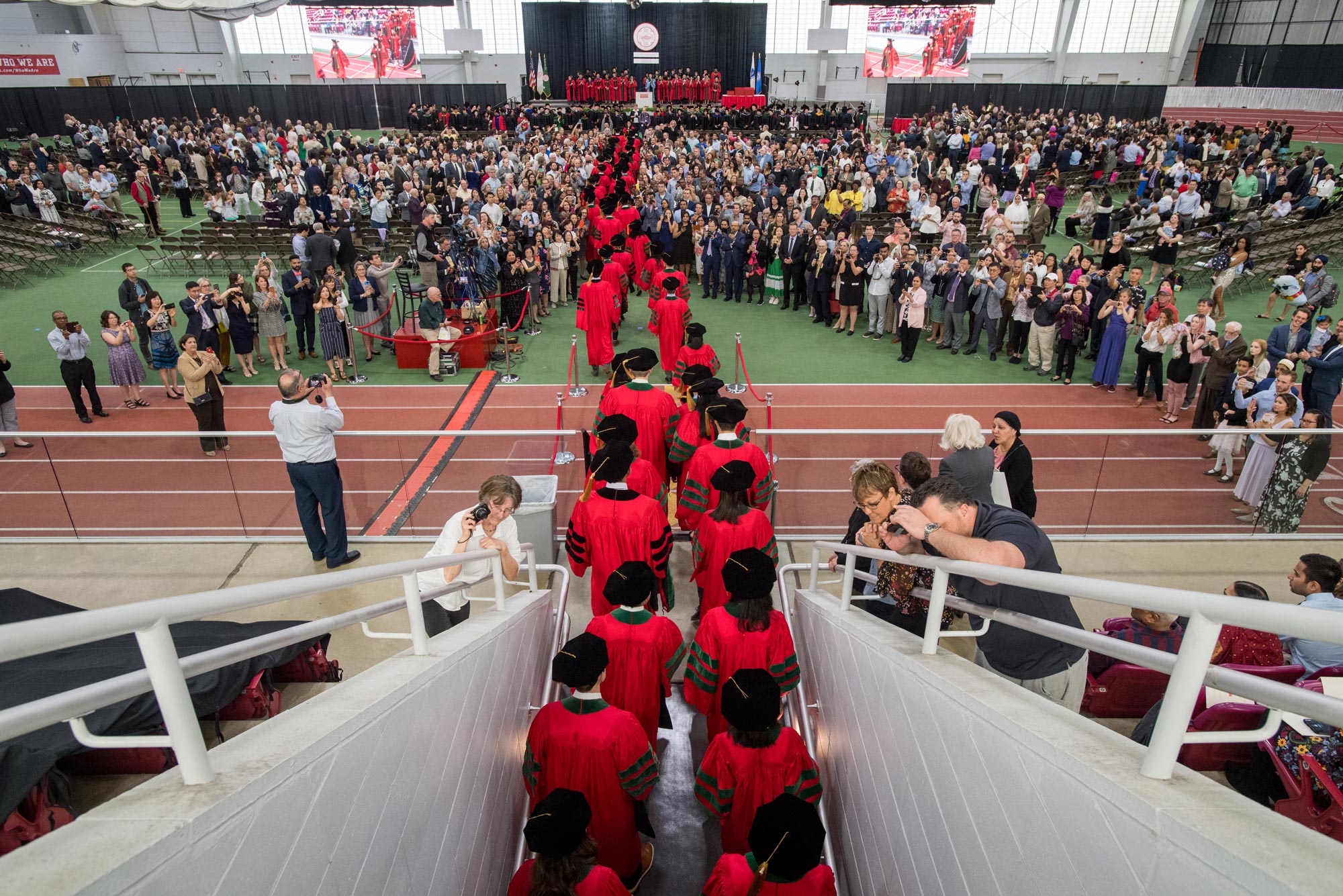 Photo of BU School of Medicine graduates walking onto the Track and Tennis Center last May during commencement.