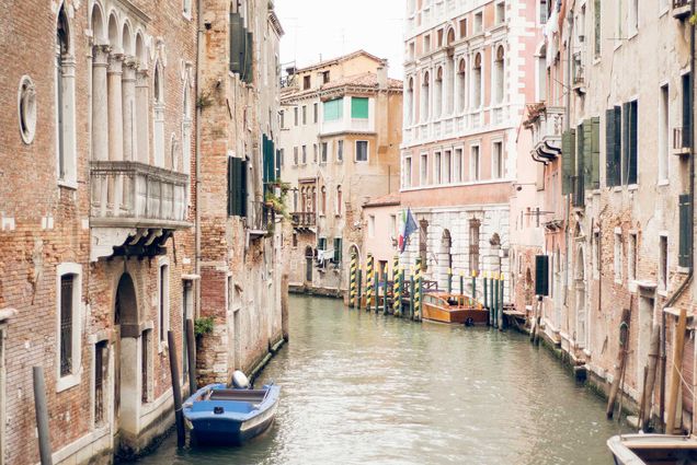 Photo of canal in Venice with two men on a blue boat in the foreground