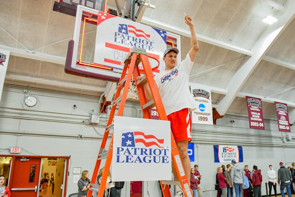 A photo of Max Mahoney cutting the net down after celebrating his team's Patriot League title