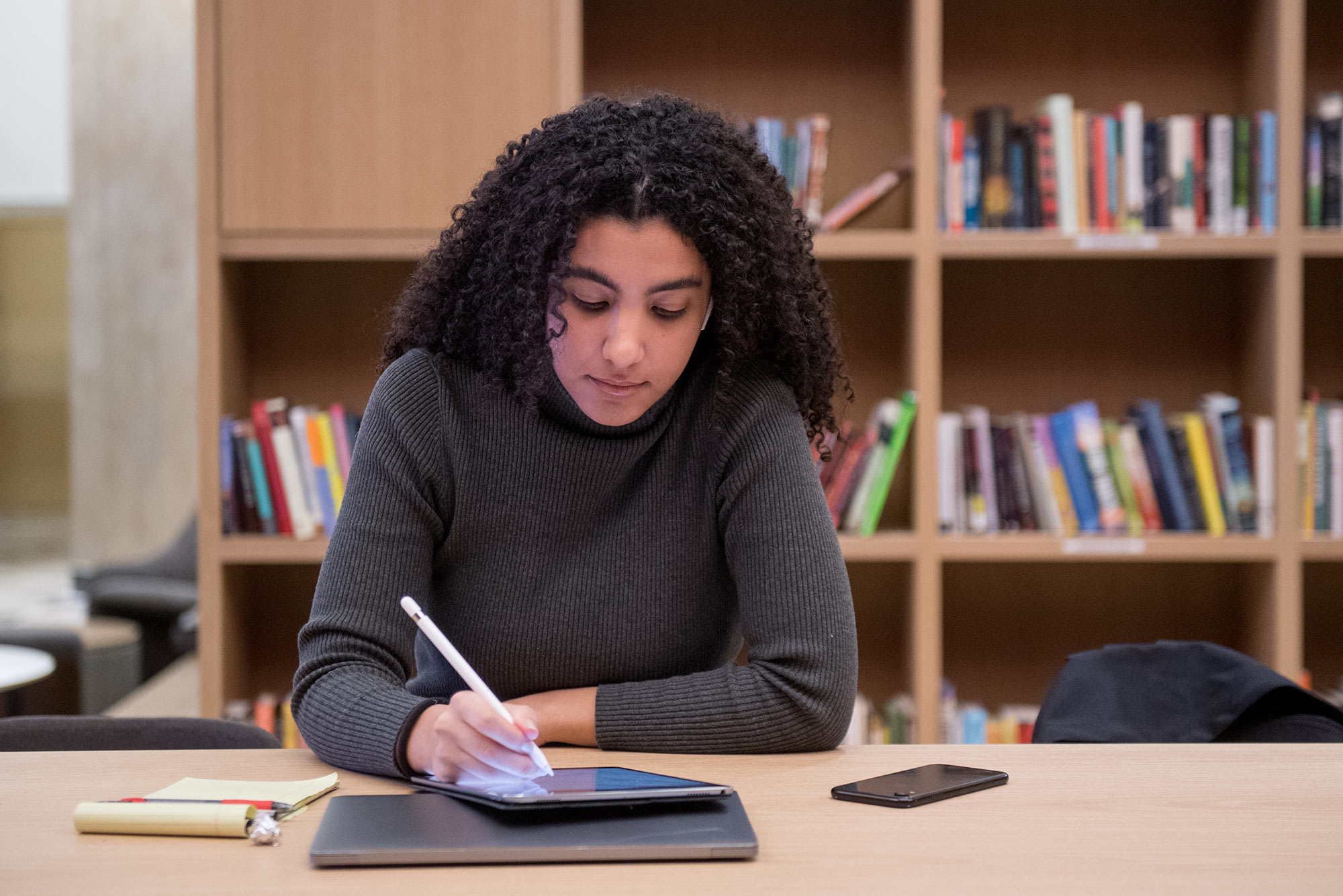 Image of Rana Boustany (ENG’21), who goes over her computer science class notes in the new Howard Thurman Center January 30, 2020. She is dressed in a gray sweater and uses a stylus on a tablet.