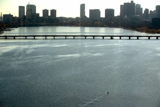 Photo of the Charles River on April 29, 2020 from a high vantage point. An erg is seen in the right bottom of the photo, and the Mass Ave bridge and Boston skyline is seen in the background.