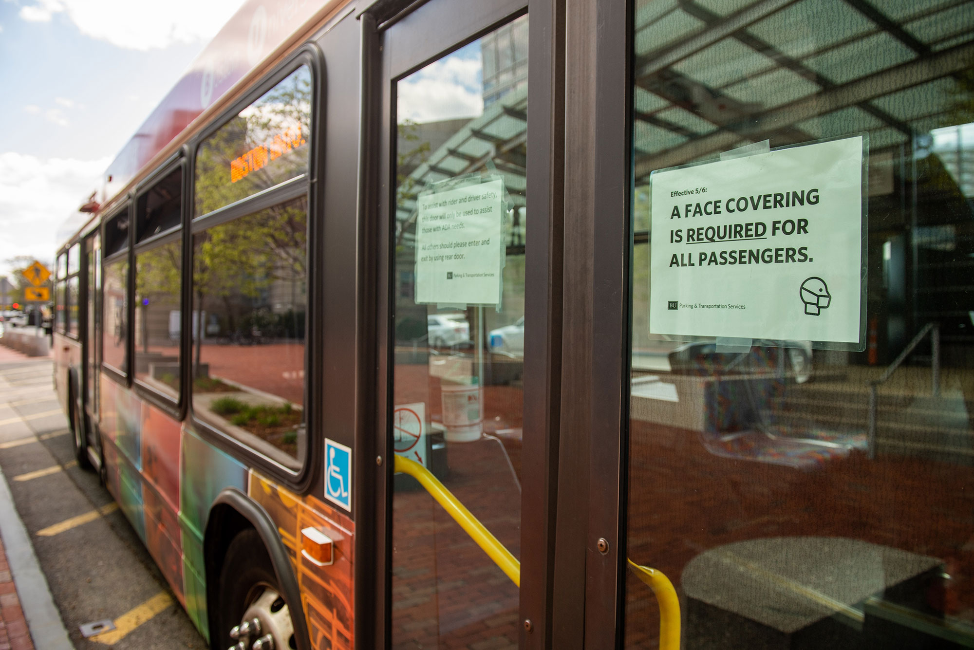 Photo of a red BU Bus with a sign that reads "A face covering is required for all passengers"