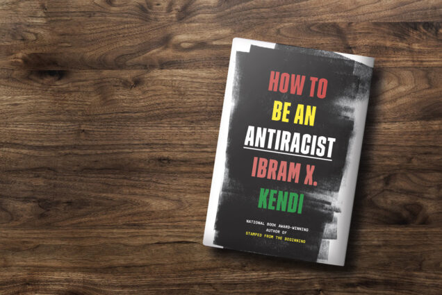 Photo of the cover of "How to Be An Antiracist" by Ibram X. Kendi resting on a grainy piece of dark wood.