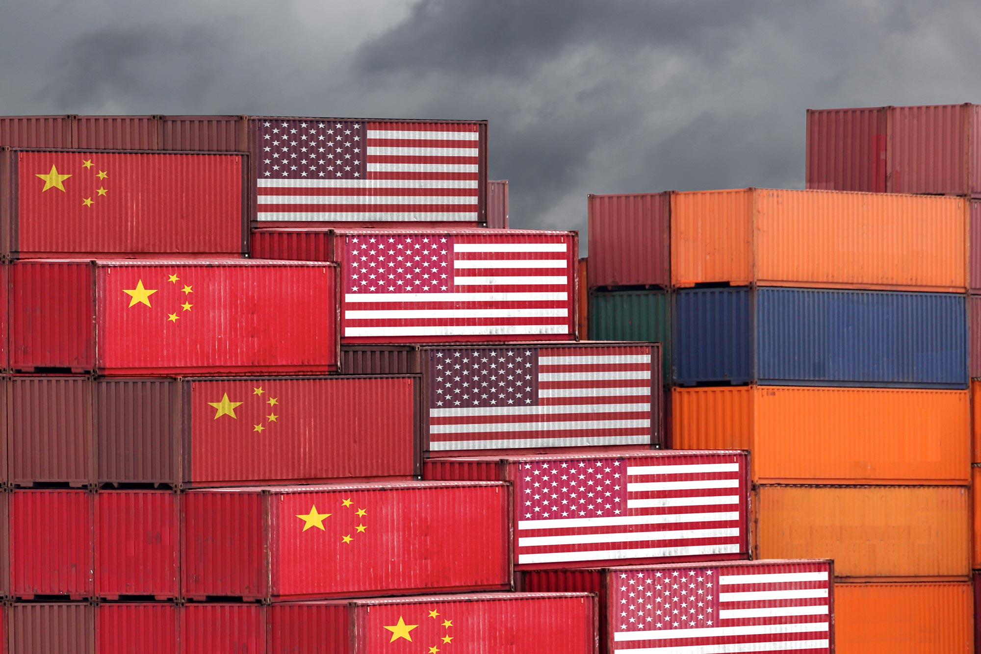 Illustrative photograph of the China USA trade war represented by cargo shipping containers painted with the American and Chinese flag stacked up near one another.