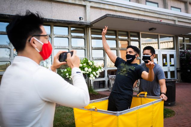 RAs Dragon Ding (CAS’21) (from left) records a video of John Issac (CAS’ 21) and Lance De Guzman (Sargent’22) on August 17. Issac stands in a yellow moving cart and De Guzman