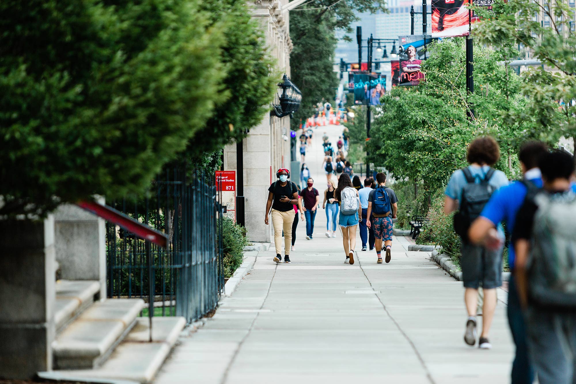 Photo of a busy sidewalk along Comm ave as students in masks walk to class.