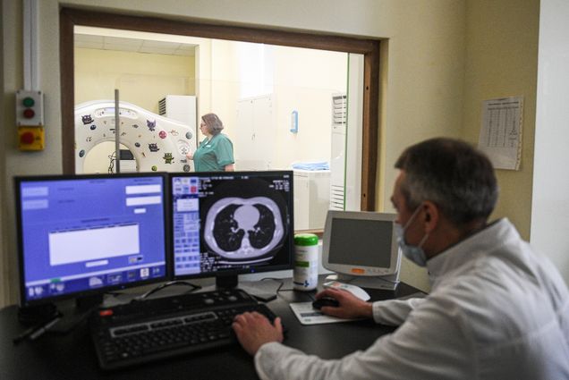 A photo of a doctor examining a CT scan of a patients lungs infected with COVID-19