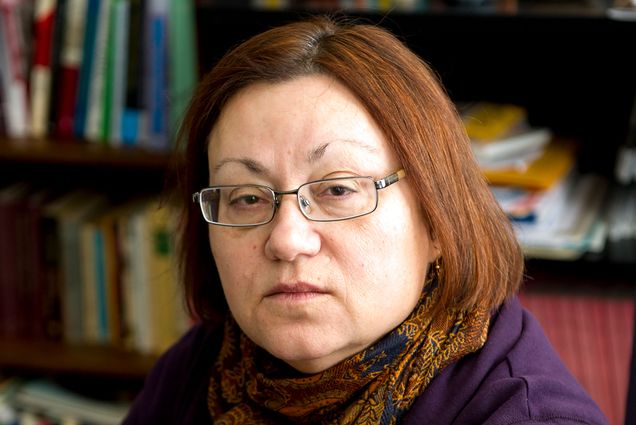 Portrait of professor Mary Beaudry, who died unexpectedly on October 20. She wears a orange colored scarf and purple sweater in her study.