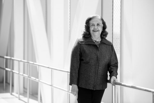 Black and white photo of Marcelle Willock, a pioneering Physician and BU Medical School Leader. She stands with her hand on a railing and smiles.