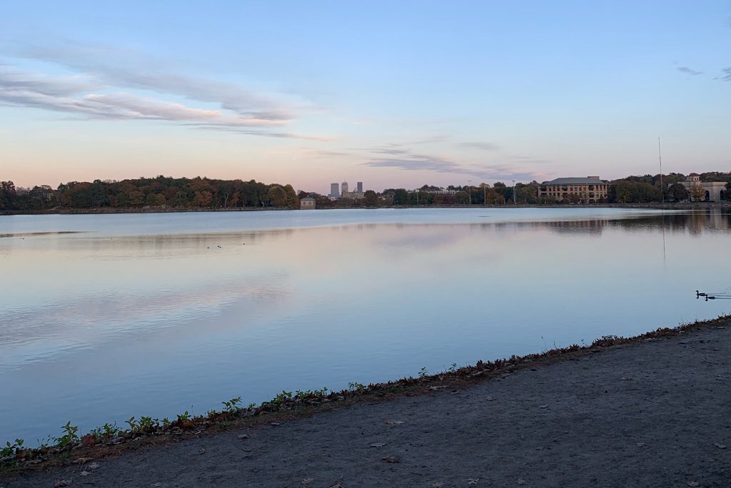 Photo of Chestnut Hill Reservoir at twilight. Blue skies fade to yellow, ducks are seen in the water.