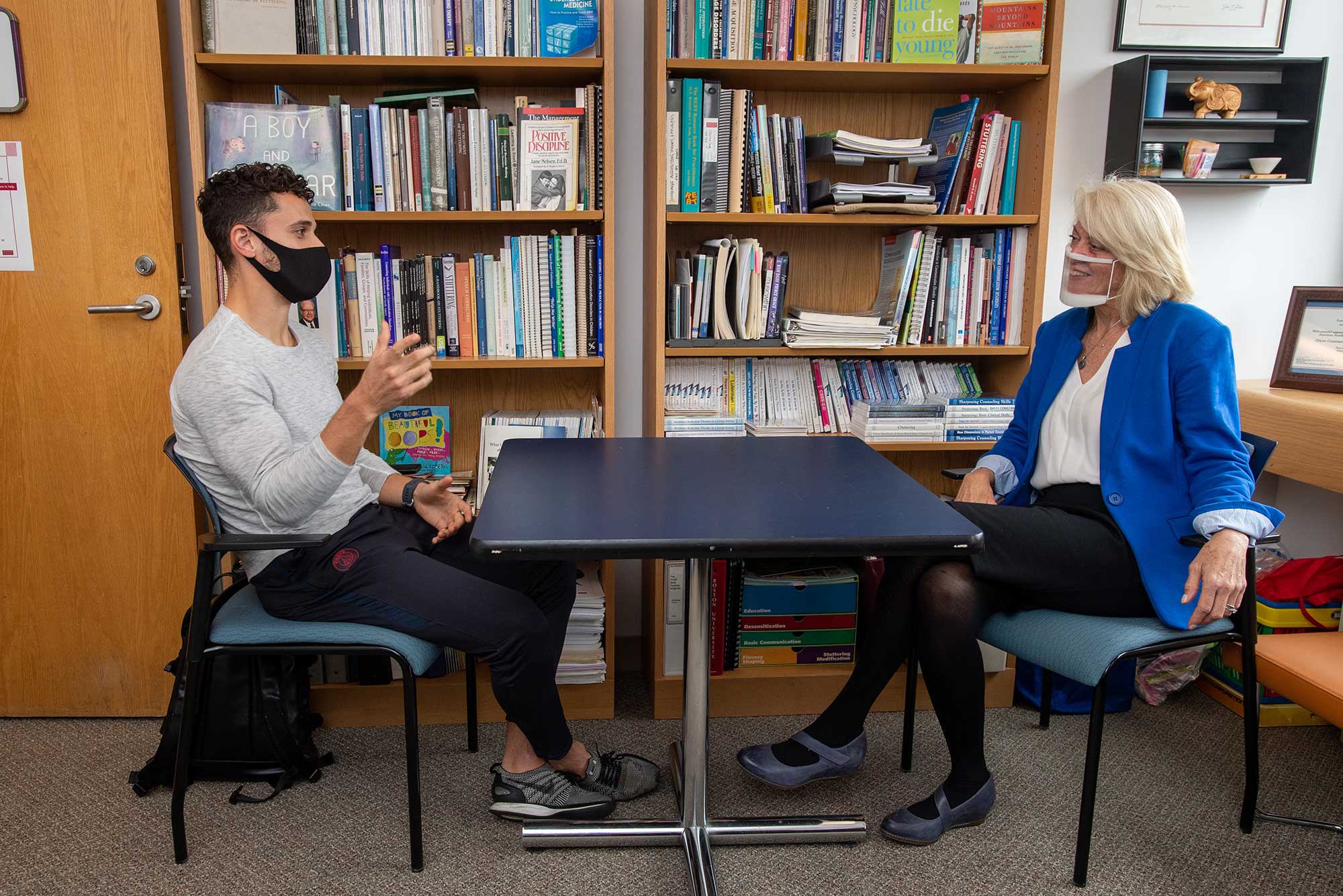 Diane Constantino (Sargent’81), director of BU’s Center for Stuttering Therapy, in her office with client Mason Blake (Wheelock’23). The two stage a therapy session. They both wear masks, Constantino wears a clear mask.