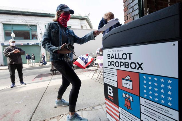 A woman places her ballot in a dropbox after voting at Fenway Park, Saturday, Oct. 17, 2020, in Boston.