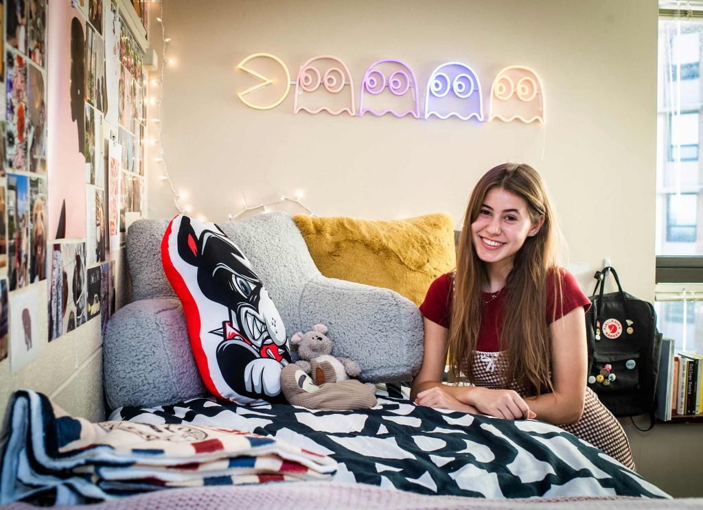 Jordan Kreindler leaning against the bed in her dorm room at Boston University