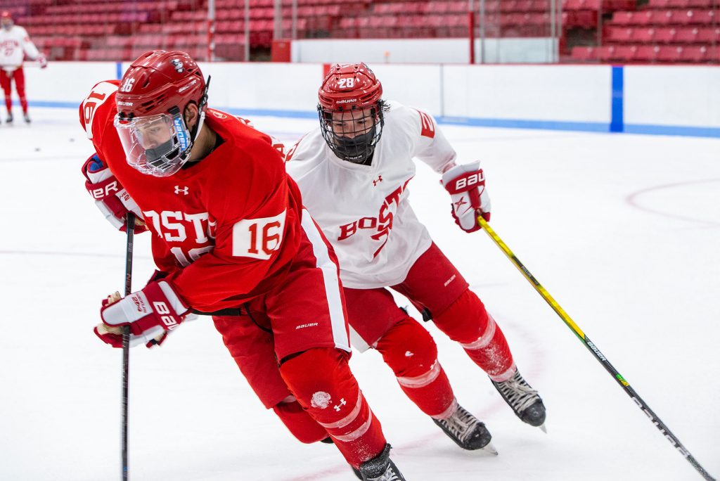 Photo of Robert Mastrosimone (SHA’23), number 16 in red, and Ethan Phillips (CAS’23), number 28 in white, wearing masks under their helmets, during a recent practice. 