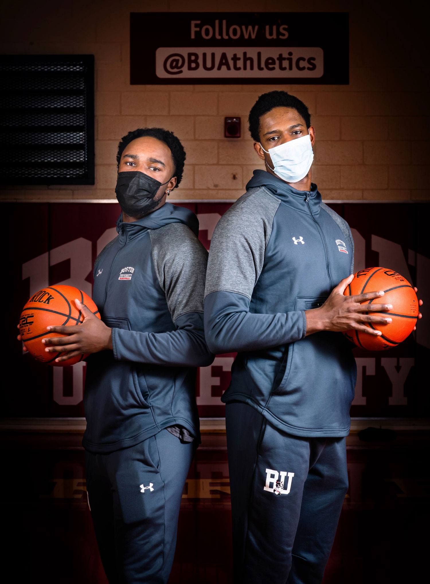 A photo of Walter Whyte and Jonas Harper standing next to one another, wearing masks, and each holding a basketball