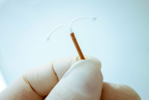 A photo of a gloved hand holding an intrauterine device