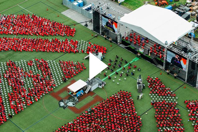 A photo of Nickerson Field from above during commencement. A white video play button is overlayed.