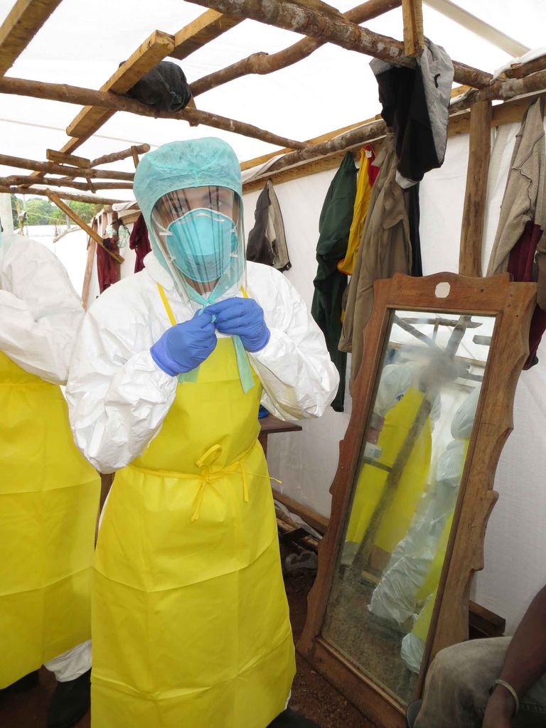 Dr. Nahid Bhadelia suits up in PPE suit, mask, gloves, and apron, in West Africa before treating Ebola patients.