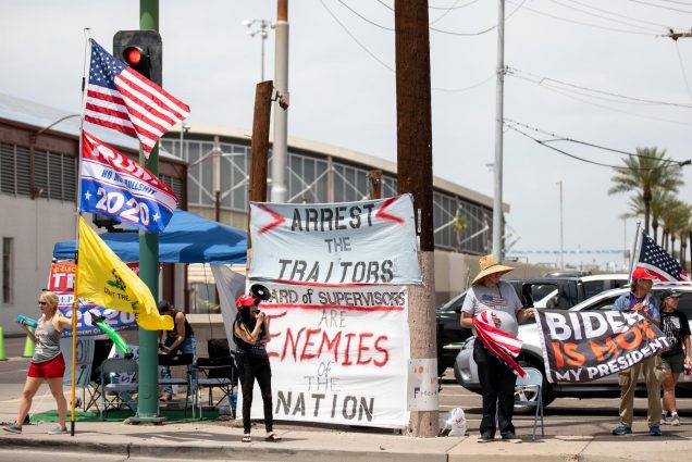 A photo of Trump supporters holding signs that read "Arrest the Traitors" and "Biden is Not My President"