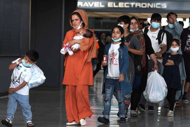 Afghan Refugees walk through the departure terminal to a bus at Dulles International Airport after being evacuated from Kabul following the Taliban takeover of Afghanistan.