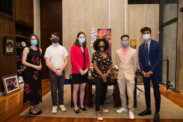 Photo of Boston Mayor Kim Janey (center) with this year’s BU City Scholars Summer Fellows Julia Sullivan (left) (Sargent’22), Chris Dew (CAS’22) and Lily Kelly (CAS’22), and BU Initiative on Cities Summer Fellows Avi Nguyen (CAS’22) and Deep Patel (CAS’22). Not in photo: Kimberly Rhoten (GRS’26). Each student wears a face mask and smiles. They are all dressed up in business attire.