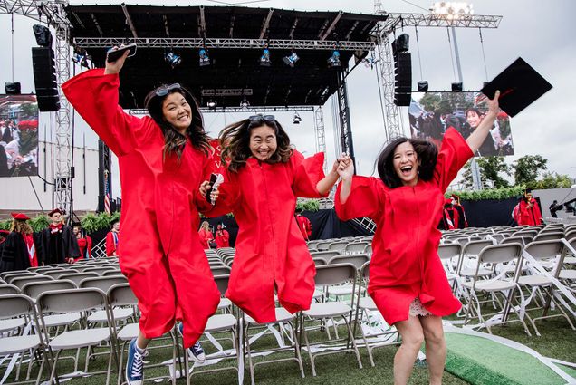 Three Boston University graduates jump in their smiling for a photo following Commencement.