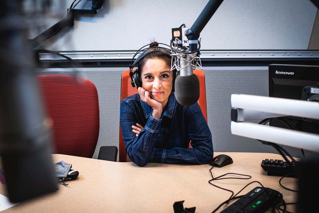 WBUR host Rupa Shenoy sits behind the microphone wearing headphones in the WBUR studio.