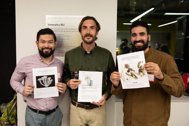 Photo of the winners of Innovate@BU’s second annual Community Impact Challenge from (l-r) Alan Mui (MBA’23), L. George Sulak (MBA’23), and Christopher Sanchez (MBA’23) All 3 smile and face the camera holding up papers detailing their submissions for the challenge.