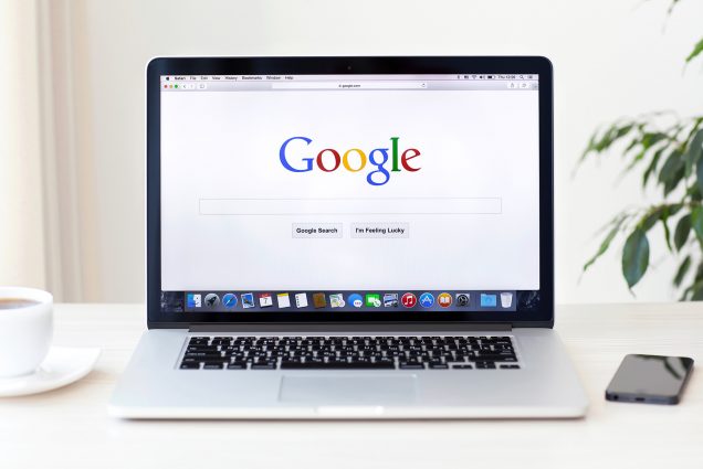 Photo of an open Apple laptop with the Google search homepage displayed on the screen.