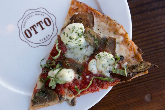 Photo of a slice of Otto's gluten-free eggplant, ricotta & basil pizza on a white plate with the Otto logo on it