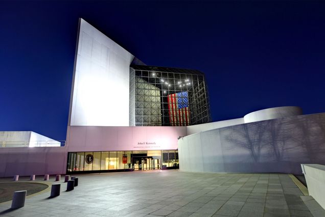 A photo of the JFK presidential museum in Boston, MA at dusk, with lights reflecting off the silver exterior