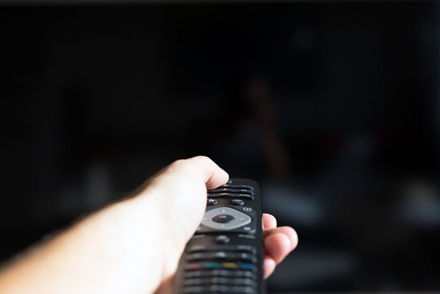 A hand holds a tv remote, pointed at a black tv screen