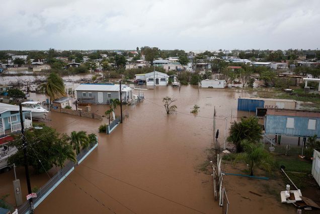 Photo of flooded streets on Salinas Beach after the passing of Hurricane Fiona in Salinas, Puerto Rico, Monday, Sept. 19, 2022. Overhead shot of houses and streets are flooded with muddy, brown water.