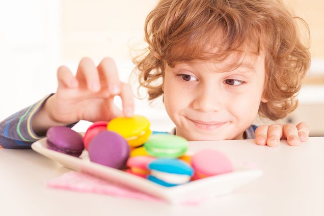 Photo of a red-headed child "stealing" cookies from a kitchen counter.