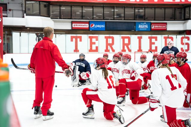 Brian Durocher, BU women’s hockey head coach, says his skaters “have been busy as all get-out, they have a good leadership group, and they're excited.” Photos by Olivia Fox/BU Athletics. Here Durocher stands in front of his team on the ice, who are kneeling.